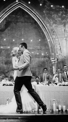 Toronto wedding couple sharing first dance in elegant historic venue with arched backdrop