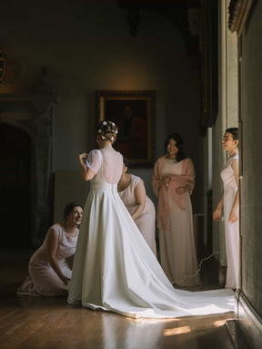 Moody candid wedding photograph of a bride and her wedding party in a historic Toronto library, softly lit by natural window light.