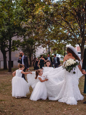Candid wedding moment of a bride and groom walking with flower girls through the lush park grounds of Exhibition Place.