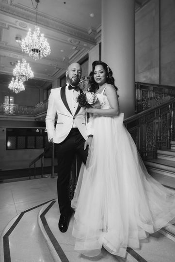 A timeless black and white documentary photograph of a bride and groom walking down a historic stone staircase together.