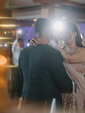 A cinematic first dance moment where a South Asian couple is surrounded by guests holding up their cell phone flashlights.