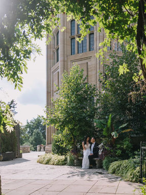 Creative bridal portrait of a bride walking down a path lined with mature trees, showcasing the movement of her high-slit gown.