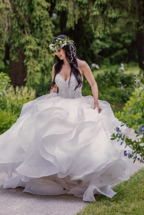 Stunning bridal portrait of a bride in a tiered tulle gown and floral crown in a whimsical garden setting.