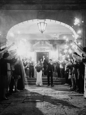 Guests hold lit sparklers creating an archway as a bride and groom walk out of a building entrance, depicting a grand exit at a reception wedding in Toronto.