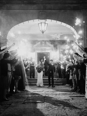 Guests hold lit sparklers creating an archway as a bride and groom walk out of a building entrance, depicting a grand exit at a reception wedding in Toronto.