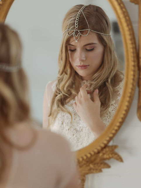 Creative mirror reflection portrait of a bride adjusting her headpiece, showcasing the artistic and detailed style of cinematic bridal photography in Toronto