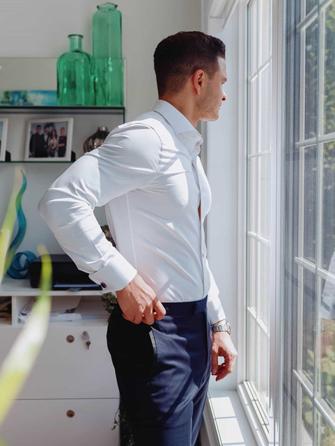 Documentary wedding photography of a groom looking out a window during morning preparations in a modern Toronto residence.