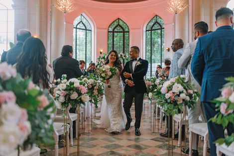 Bride walking down the aisle during a floral-filled wedding ceremony in the Casa Loma Conservatory.