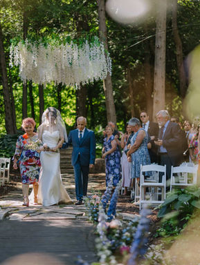 A radiant bride holding her bouquet while standing in a beautiful, snow-covered forest during a winter wedding celebration.