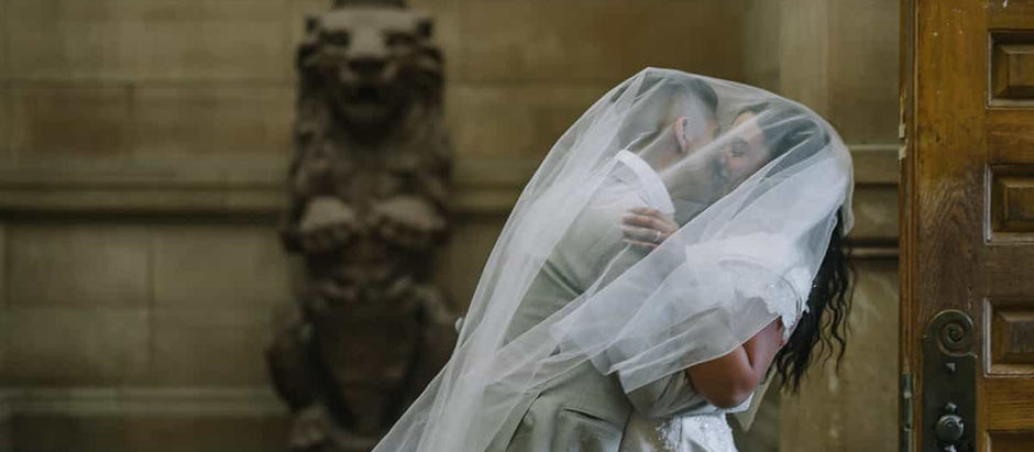 bride and groom kissing under veil in old city hall lobby