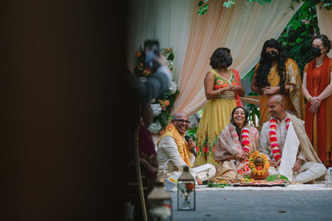 A beautiful documentary photograph of a traditional South Asian wedding ceremony ritual taking place under the glass roof of the greenhouse.