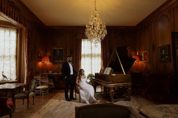 Bride sitting by a grand piano in a historic vintage study room. Classic wedding photography in Toronto.