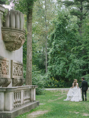 A romantic back view of a couple walking toward the towering stone ruins and historic monuments at Guild Park and Gardens.