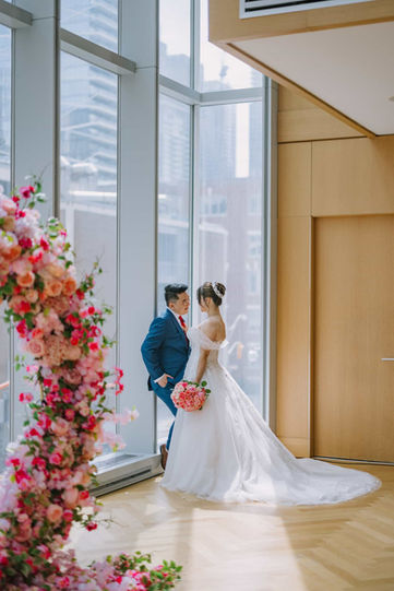 Romantic wedding photography of a couple looking out the floor-to-ceiling windows of the Museum Room with the Toronto city skyline behind them.