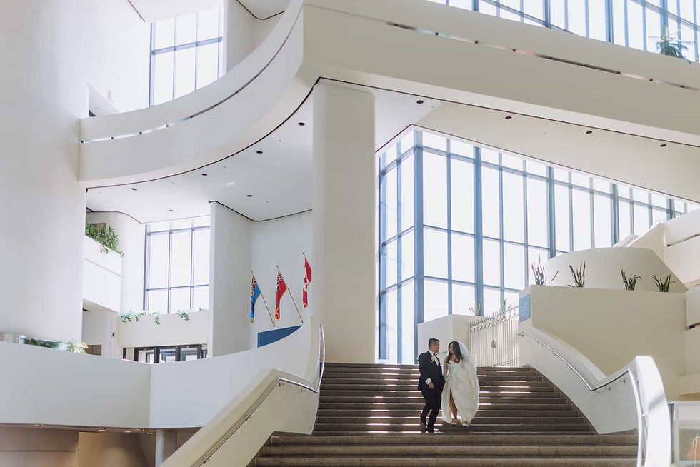 bride and groom walking down staircase in bright lobby