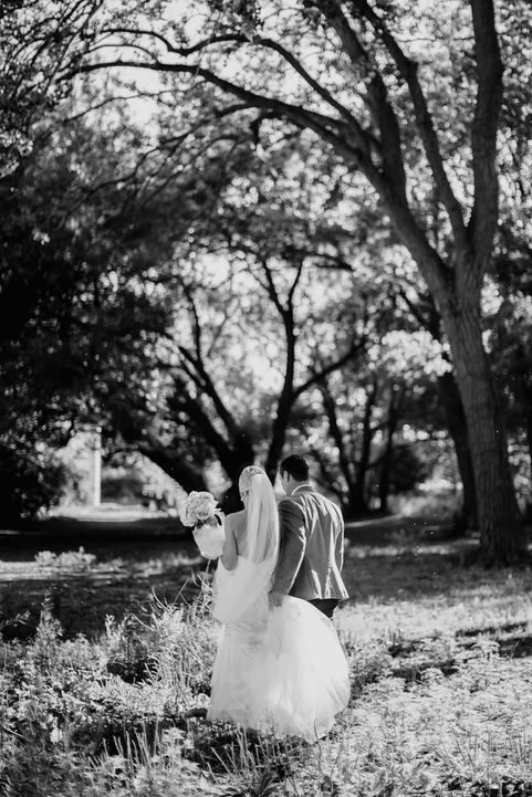 Timeless black and white candid portrait of a couple nestled beneath a large, leafy tree in a scenic Toronto park.