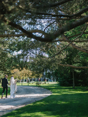 A romantic wedding portrait of a bride and groom embracing beside a historic wooden four-poster bed inside the Tudor mansion.