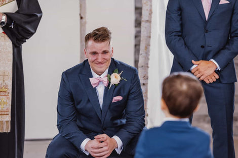 Emotional candid of a groom at the altar, capturing his reaction as he watches the bride walk down the aisle.