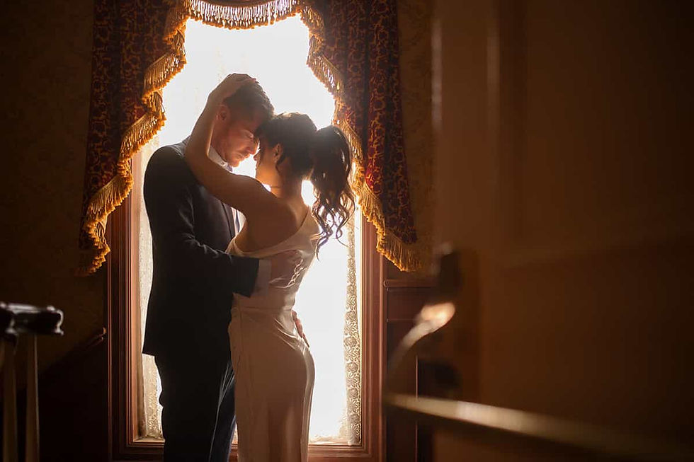 Cinematic silhouetted wedding portrait of a couple embracing in front of a grand historic window, captured by Toronto wedding photographer Lucas T Photography