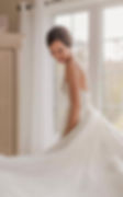 A joyful bride smiling candidly in soft natural light, her modern wedding dress flowing around her.