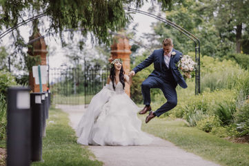 Fun and playful candid of a groom jumping for joy as the bride laughs beside him in the Heritage Gardens.