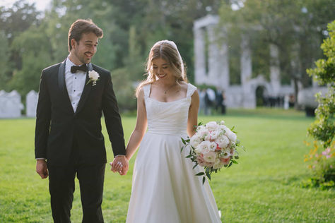 Joyful candid moment of a bride and groom holding hands while walking through the manicured Heritage Gardens in Scarborough.