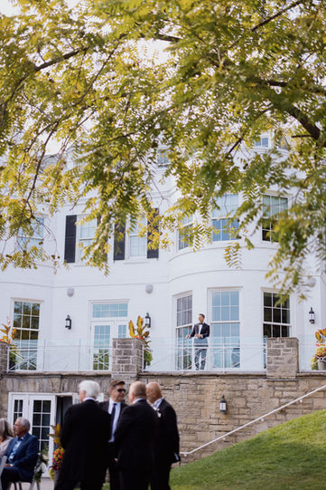 An elegant wedding couple posing outside a grand white mansion with classic architecture, a beautiful scene for a GTA wedding photographer