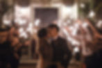 Bride and groom kissing surrounded by guests holding sparklers in a festive outdoor evening setting. Romantic, joyful atmosphere.
