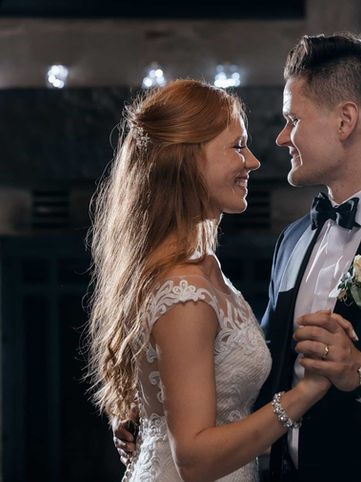 A warm close-up wedding portrait of a bride and groom smiling and looking into each other's eyes during their reception first dance.
