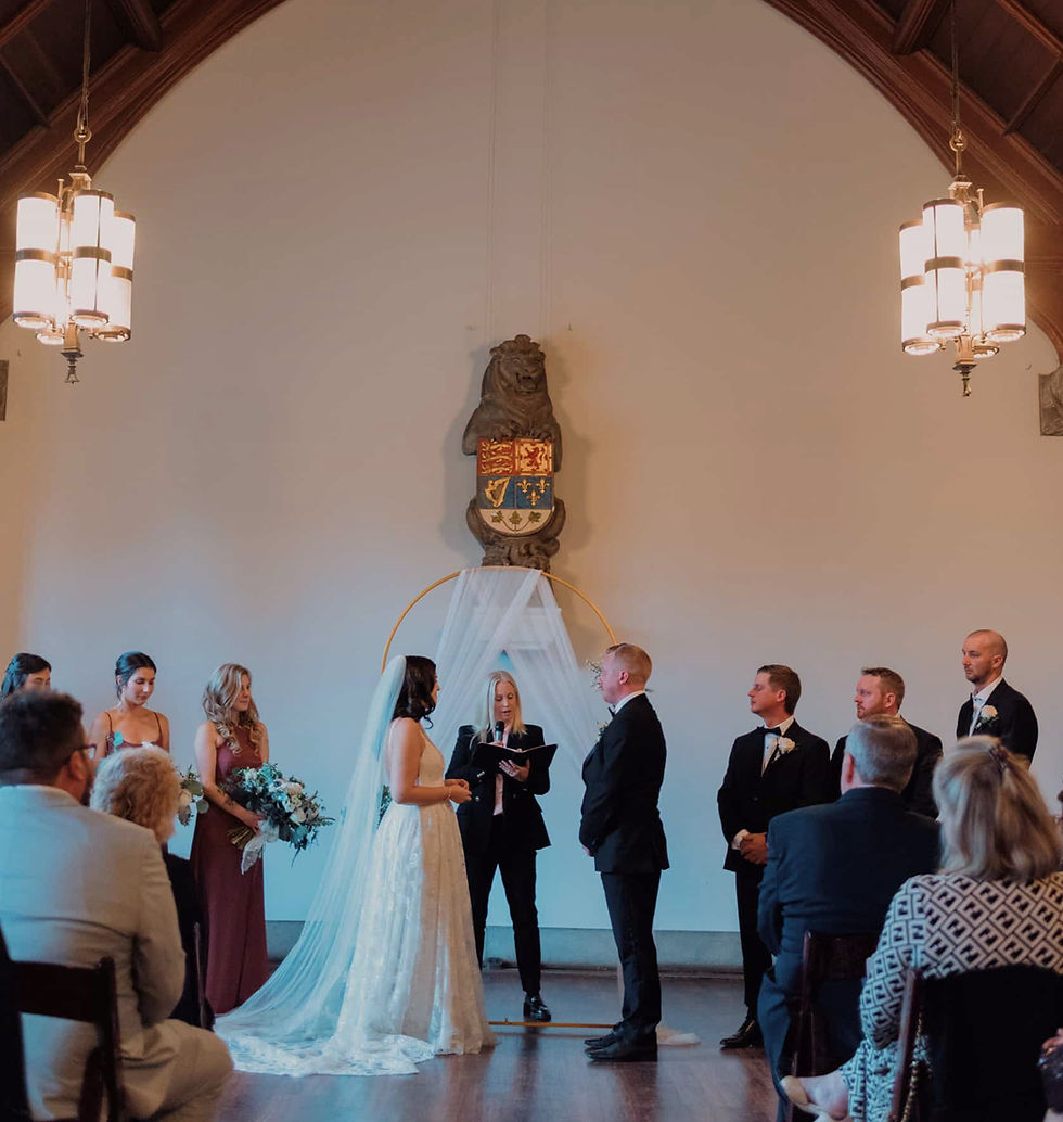 Bride and groom posing by the historic grand window at Hart House Great Hall for their wedding photos.
