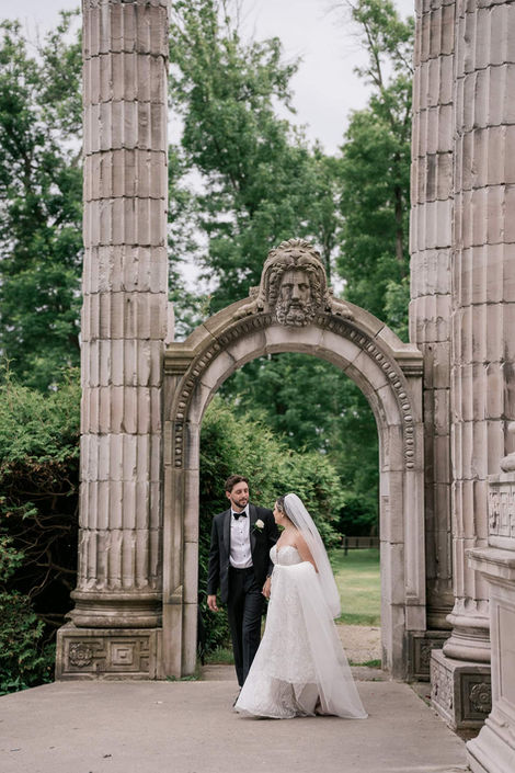 Cinematic wedding portrait of a couple standing under the iconic Greek Theatre stage featuring historic Corinthian columns.