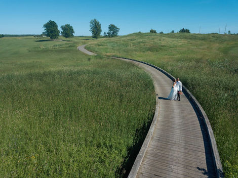 Aerial drone photography following a wedding couple along a scenic boardwalk in a Toronto area park