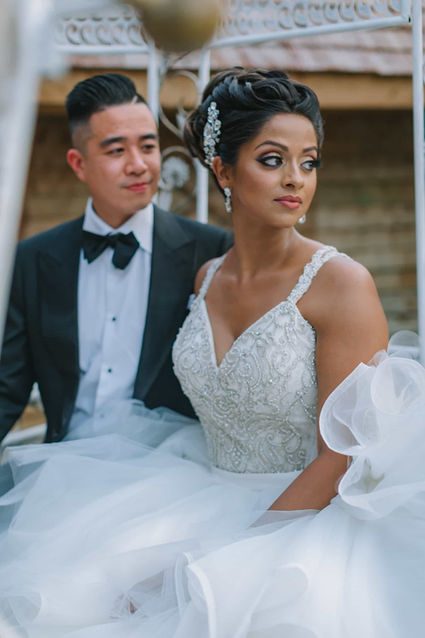 A close-up romantic wedding portrait of a bride in an embellished gown and her groom posing together inside the venue.