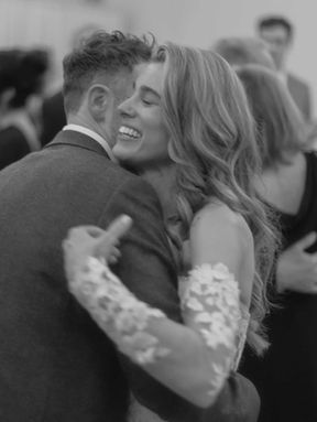Black and white candid photo of a bride and groom dancing joyfully in a crowd of guests at a Toronto wedding reception.