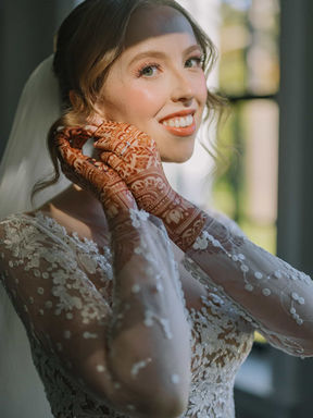 beautiful close-up portrait of a bride looking over her shoulder, highlighting her elegant lace sleeve and intricate mehndi hand designs