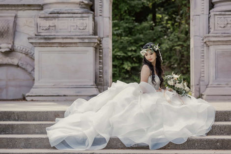 Editorial-style bridal portrait of a bride sitting gracefully on the weathered stone steps of a historic monument.