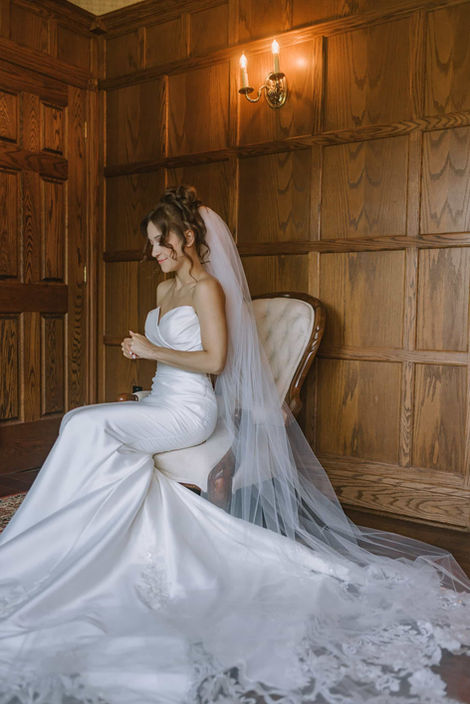 Bride sitting in an intimate dark wood-paneled room