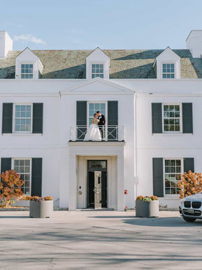 White mansion wedding venue facade with bride and groom on balcony
