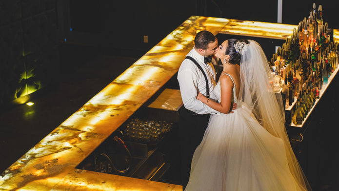 groom and bride standing on bar kissing