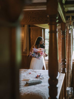 A breathtaking back-view photograph of a bride walking alone down a stone path toward an empty, enchanted forest ceremony altar.