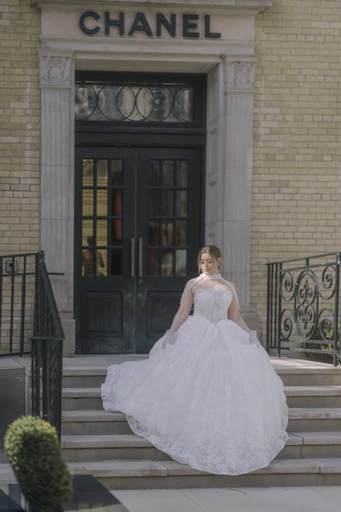 A bride wearing a tulle ballgown standing on the stone steps of a city building for an urban wedding photography session in downtown Toronto.