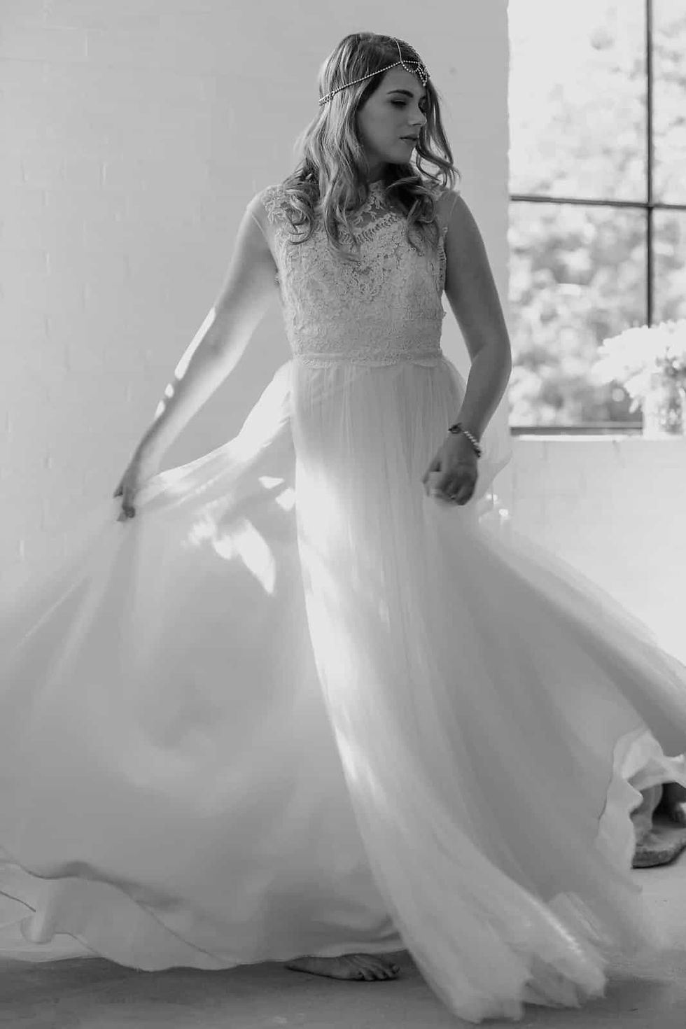 Bright outdoor bridal portrait of a smiling blonde bride with wavy hair wearing an off-the-shoulder lace wedding dress at High park