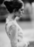 An elegant, black and white bridal portrait by a Toronto wedding photographer, featuring a bride in profile with a delicate lace, long-sleeve wedding dress and an intricate updo
