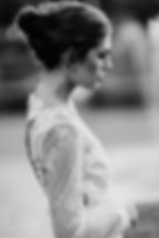 An elegant, black and white bridal portrait by a Toronto wedding photographer, featuring a bride in profile with a delicate lace, long-sleeve wedding dress and an intricate updo