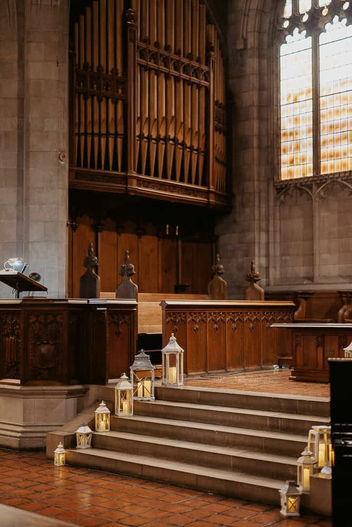 Interior detail of the wood-paneled choir area and organ at Trinity College Chapel, decorated with wedding lanterns.