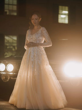 A cinematic evening portrait of a bride standing in a spectacular beam of light outside the historic estate venue.