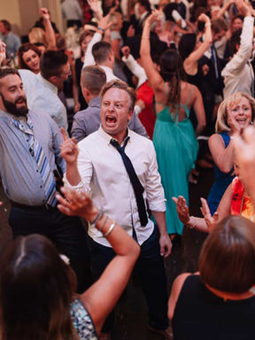 Vibrant candid photography of guests dancing and celebrating with hands raised at a modern Toronto wedding reception.