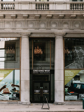  Majestic interior of the Grand Banking Hall at One King West featuring 45-foot ceilings, Corinthian columns, and purple event lighting.