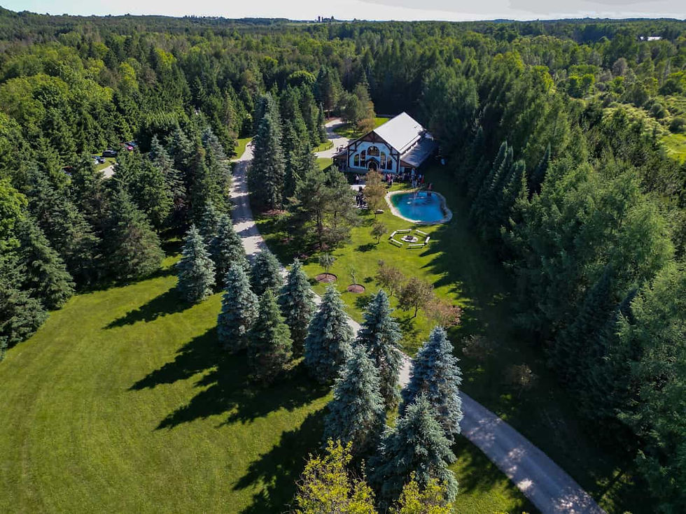 Aerial view of the barn-style wedding venue and pond at Erin Estate surrounded by forest.