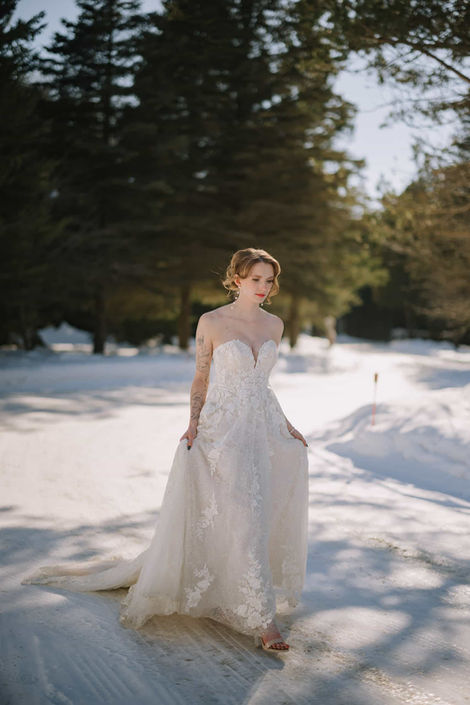 Bride in white dress standing by a snowy manor house